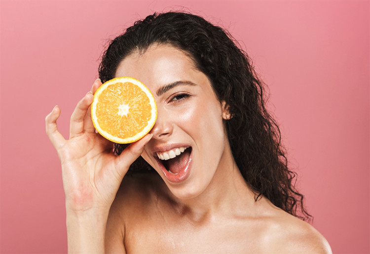 Woman holding an orange to her eye.