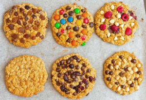 Six cookies on a backing tray with different toppings.