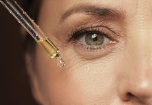 Woman applying face serum near eye.