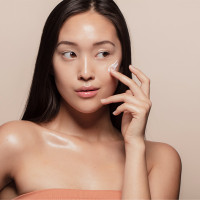 Korean woman applying face cream.