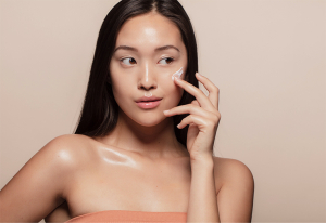 Korean woman applying face cream.