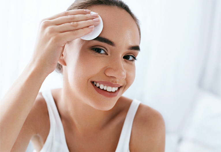 Woman applying toner to her face with a pad.