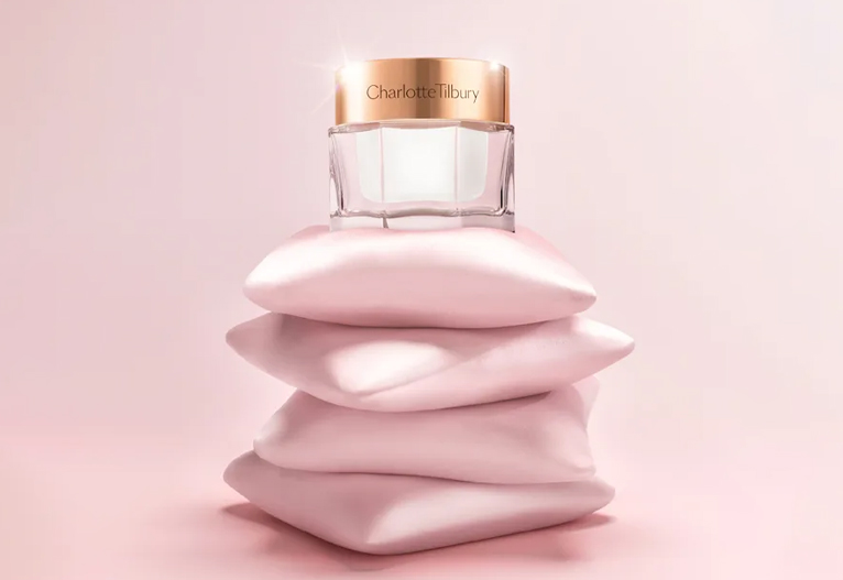 Charlotte Tilbury Magic Cream on top of a pile of silk pillows.