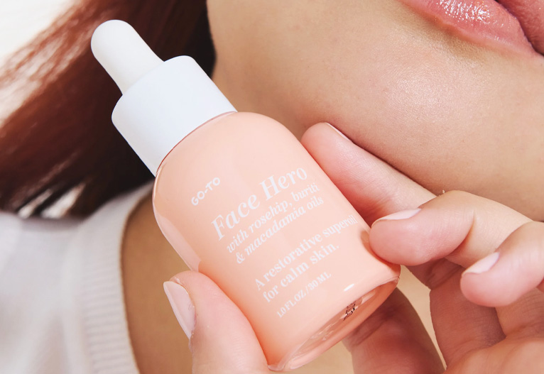 Person holding a bottle of Face Hero from Go-To Skincare.