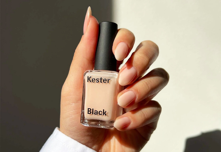 Person holding a bottle of Kester Black nail treatment.