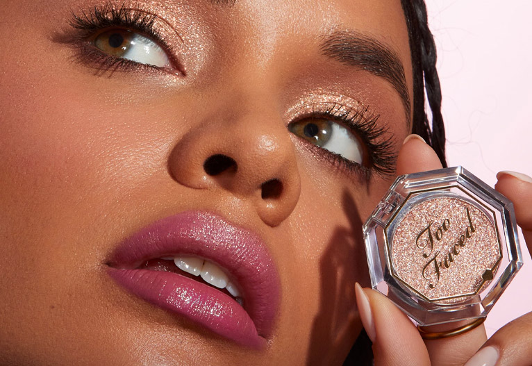 Model holding palette of Disco Crush Glitter eyeshadow by Too Faced.
