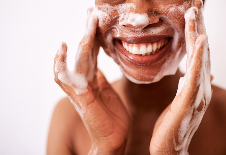 Smiling woman washing her face.