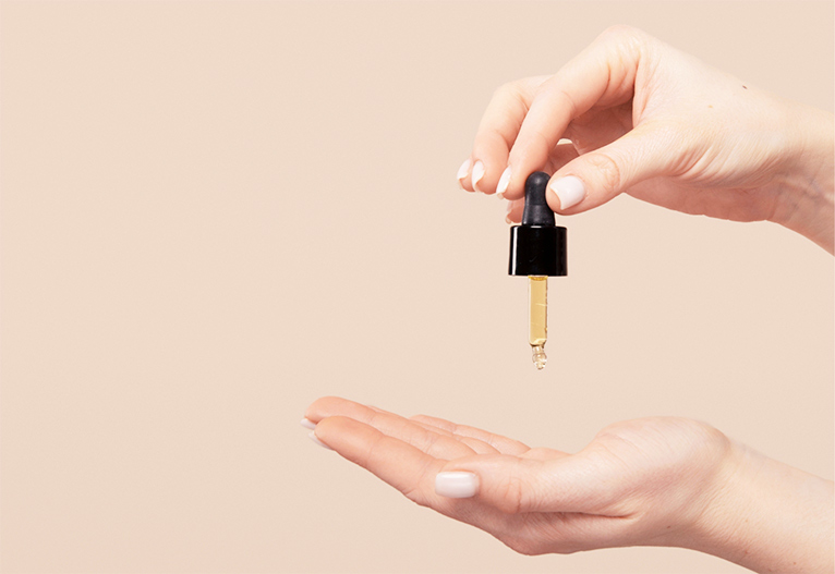 Person using a dropper to dispense serum onto hand.