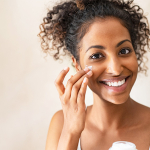 Woman applying moisturiser to her face.