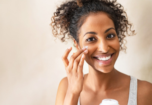Woman applying moisturiser to her face.