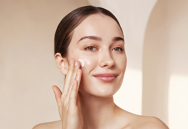 Woman applying moisturiser to her face.