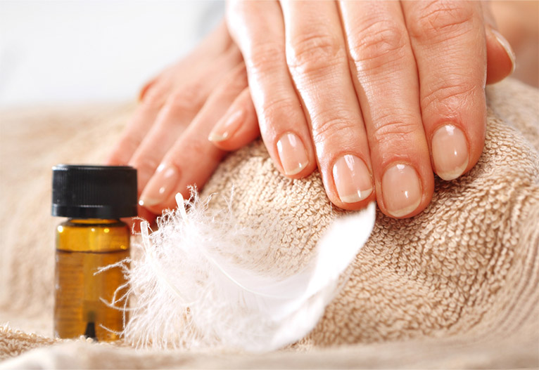 Person with healthy nails next to a bottle of nail serum.