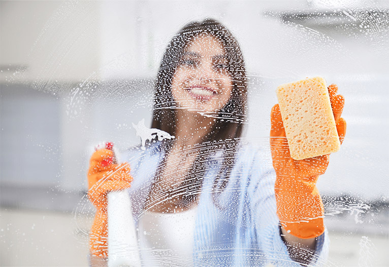 Woman cleaning a window with gloves on.