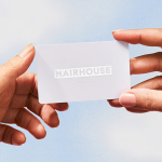 Person holding a Hairhouse gift card up to the sky.