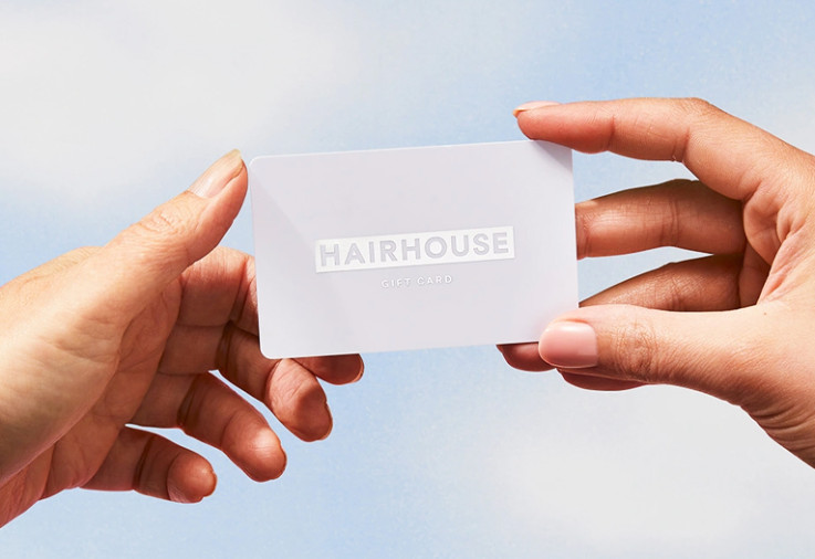 Person holding a Hairhouse gift card up to the sky.