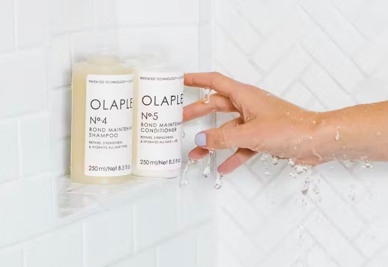 Person reaching for Olaplex products in the shower.