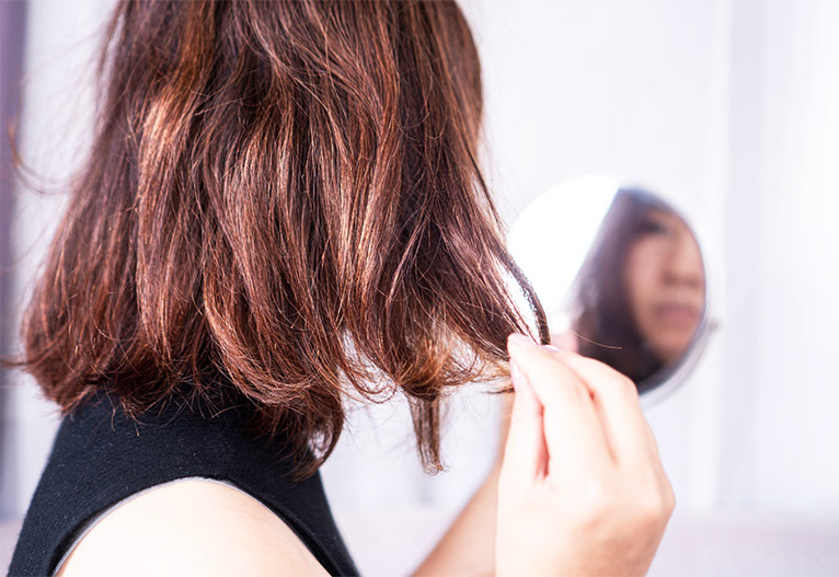 Woman touching her dry hair.
