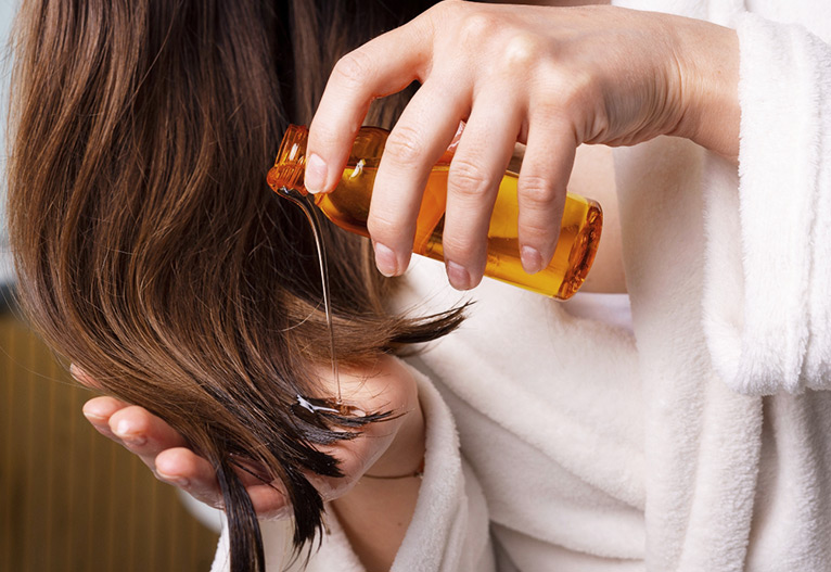 Person pouring oil on hair ends.