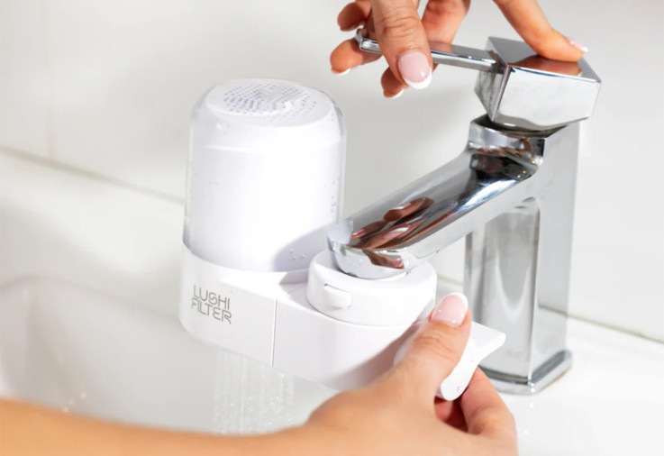 Person using the Lushi Skincare Water Filter on a bathroom tap.