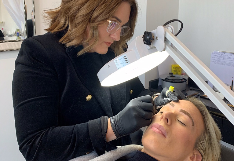 Kim Evans working on a client's eyebrows.