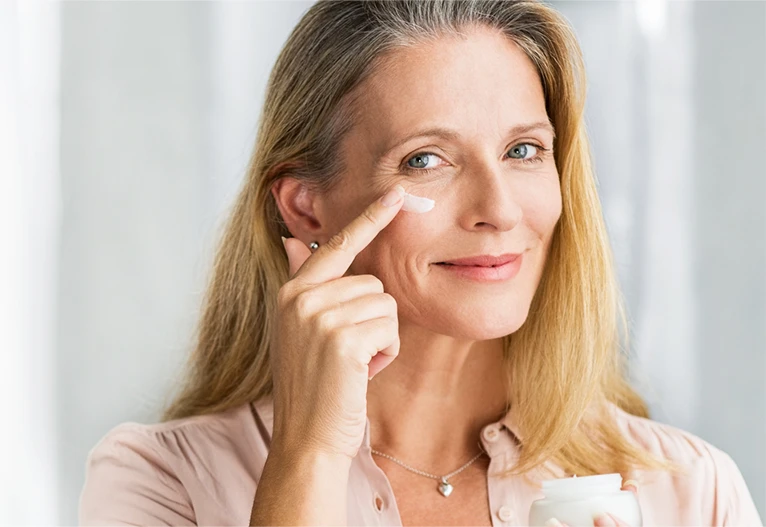 Mature woman applying face cream.