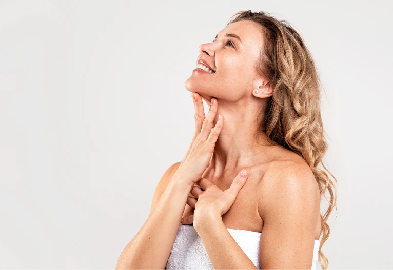 Mature woman in a towel running her hands down her neck.