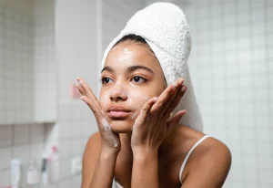 Woman washing her face in a bathroom.